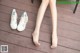 A woman's legs and shoes on a wooden deck.