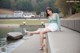 A woman sitting on a concrete wall next to a body of water.