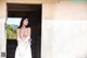 A woman in a white dress standing in a doorway.