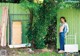 A woman standing in front of a green fence.