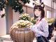 A woman in a cat ears outfit holding a large pumpkin.