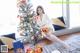 a woman sitting on the floor next to a christmas tree