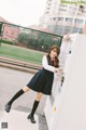 A woman in a school uniform leaning against a vending machine.