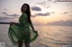 A woman in a green dress standing in the water.