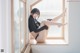 A woman sitting on a window sill with her legs up.