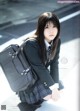 A young woman in a school uniform with a backpack.