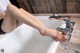 A woman is sitting in a bathtub with her feet in the water.