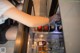 A woman is opening the door of a refrigerator filled with drinks.