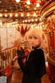 A woman with pink hair standing in front of a carousel.